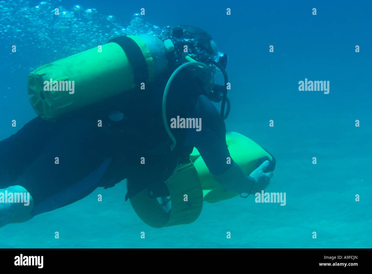 a scuba diver uses an underwater scooter to propel himself through