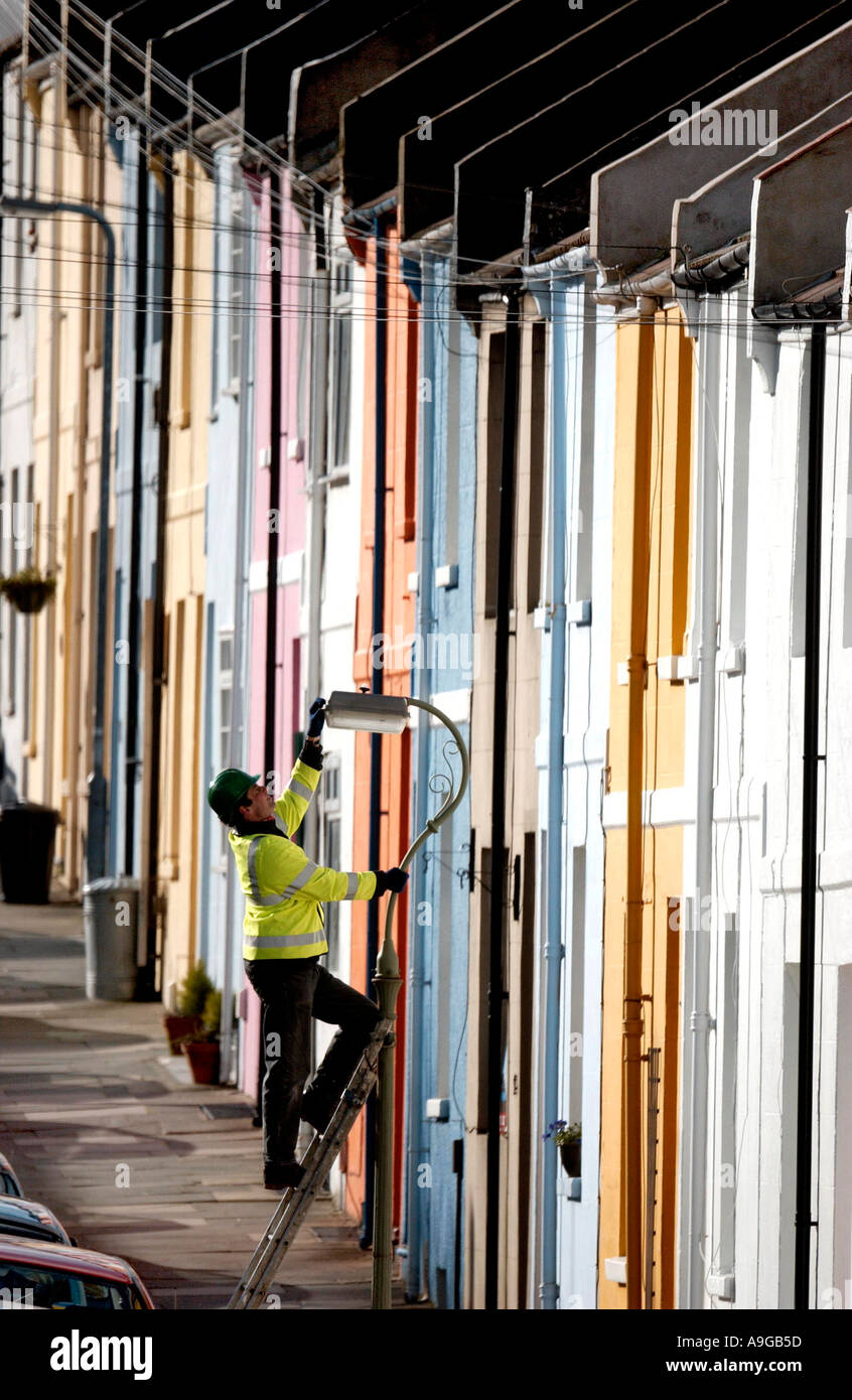 Brighton and Hove City Council worker Alan Stone checks a street lamp on a road of  brightly painted terrace houses in Brighton Stock Photo