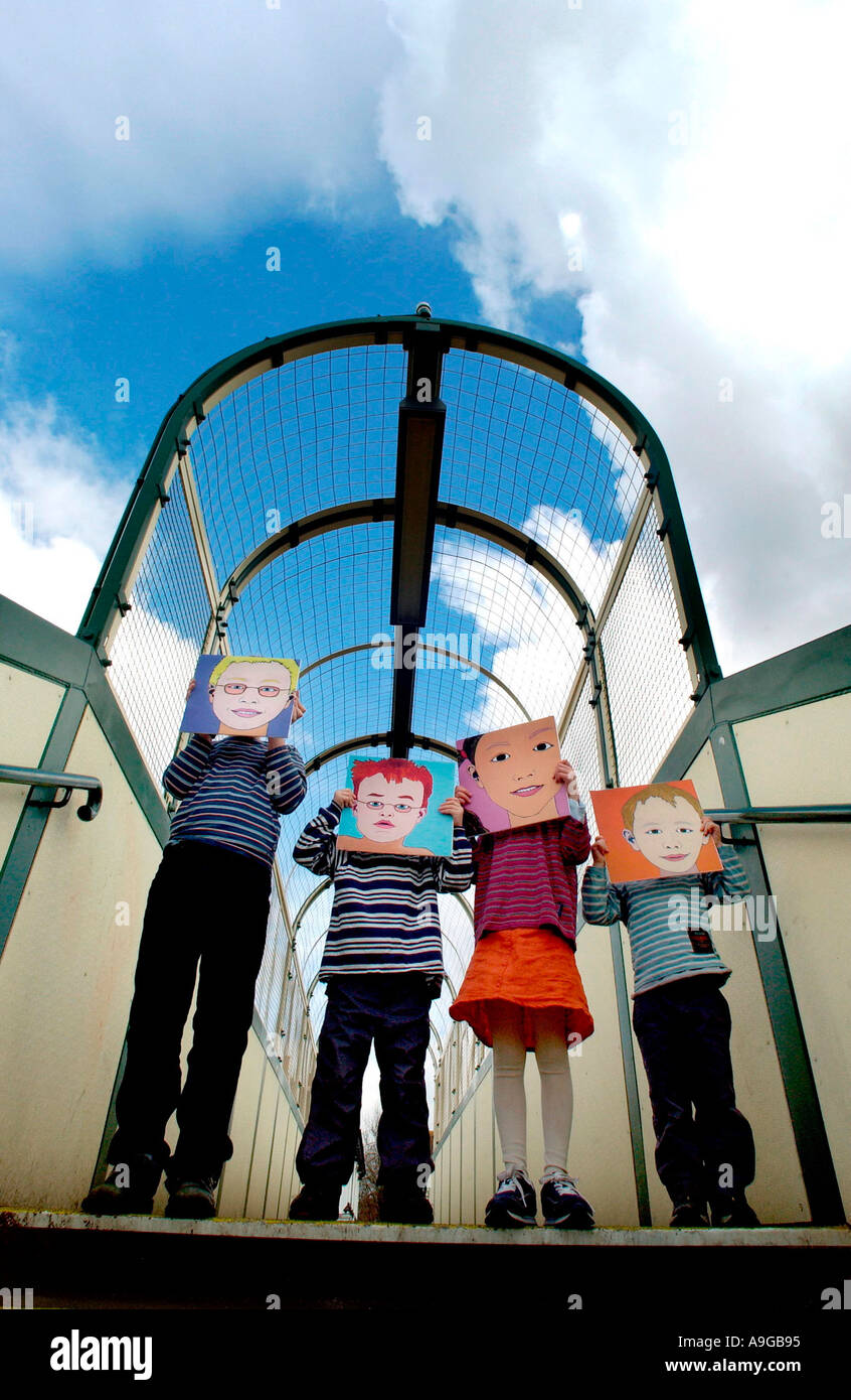 Children holding masks in front of their faces on a bridge Stock Photo