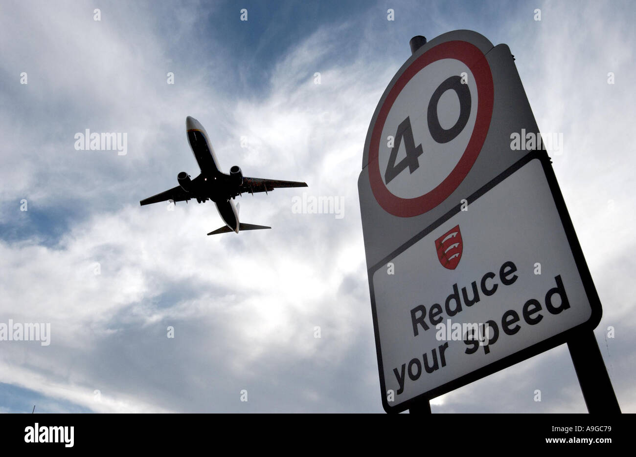 Plane flying low over a  40mph speed limit traffic sign at London Stanstead airport Stock Photo