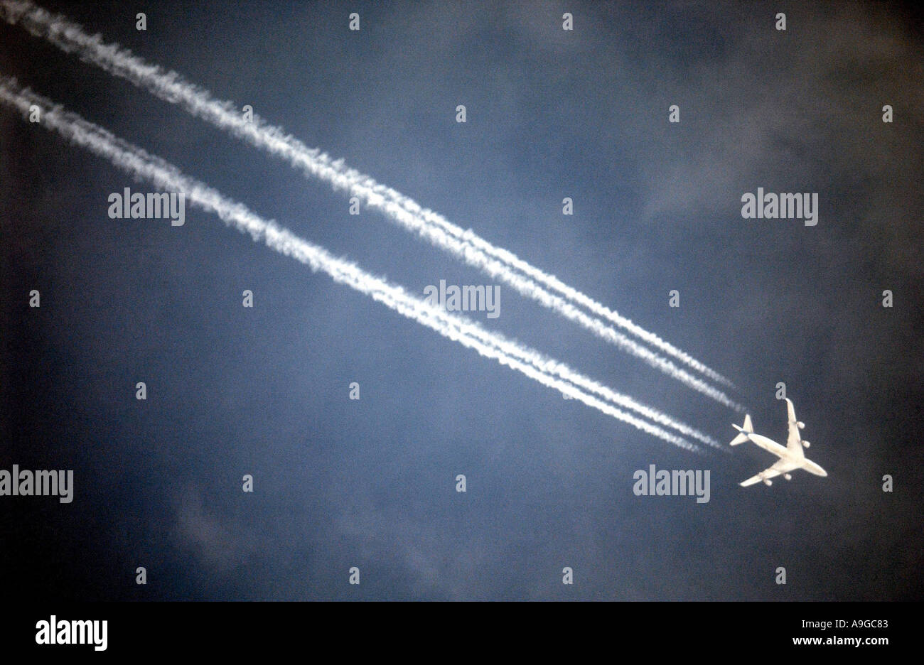 A plane coming in to land at Stansted airport leaving a jetstream behind it Stock Photo