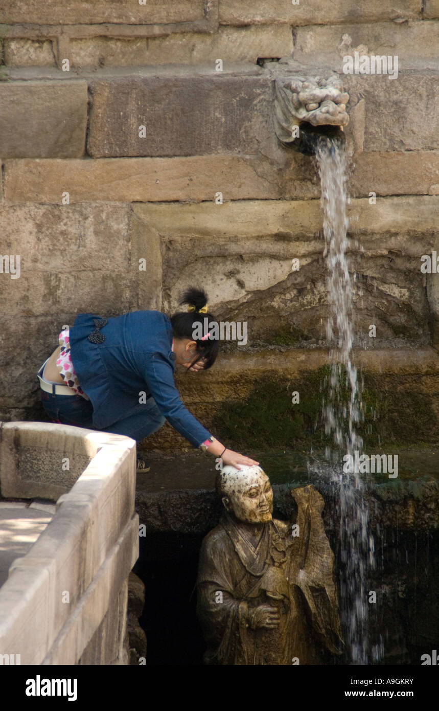 Girl rubbing statue for good luck at Jin Ci Jin Temple near Taiyuan