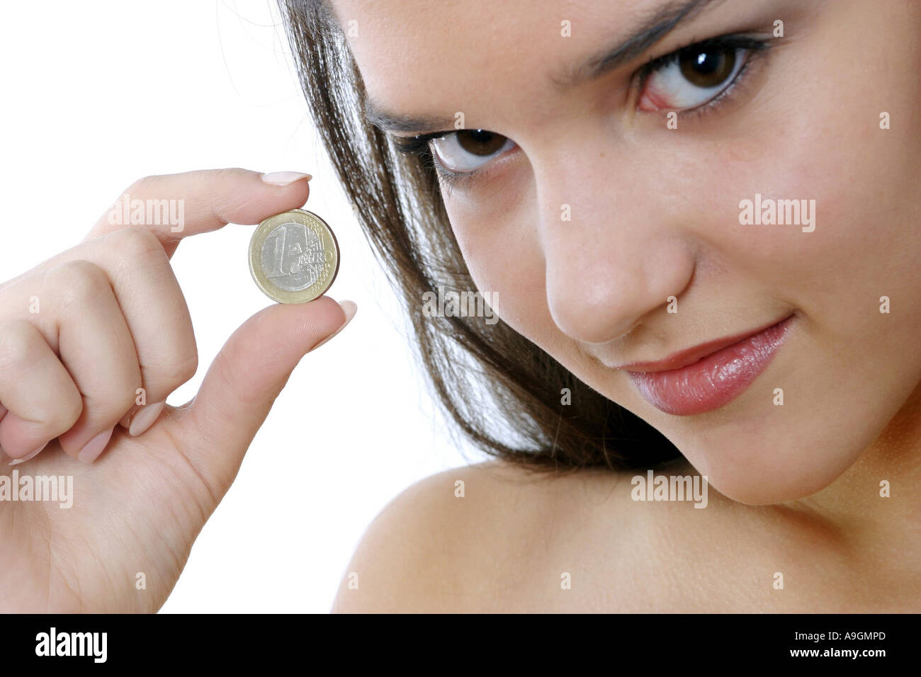 young woman holding Euro coin, looking toward camera Stock Photo