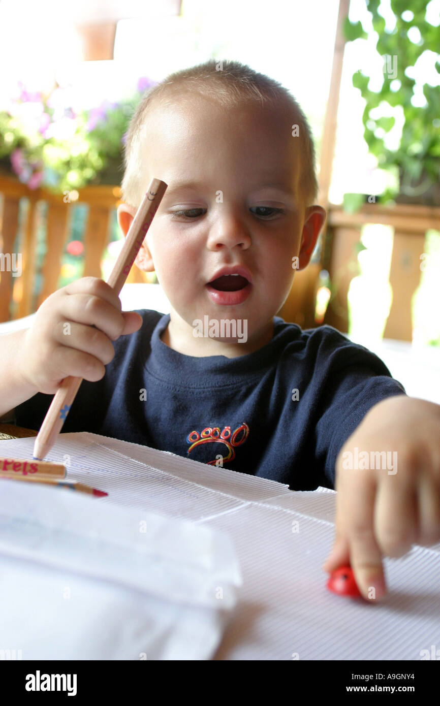 young boy holding coloured pencil, playing with toy-maybeetle Stock Photo