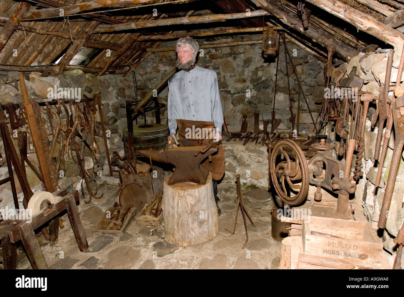 Blacksmith in old Smithy with tools in traditional crofters barn Stock