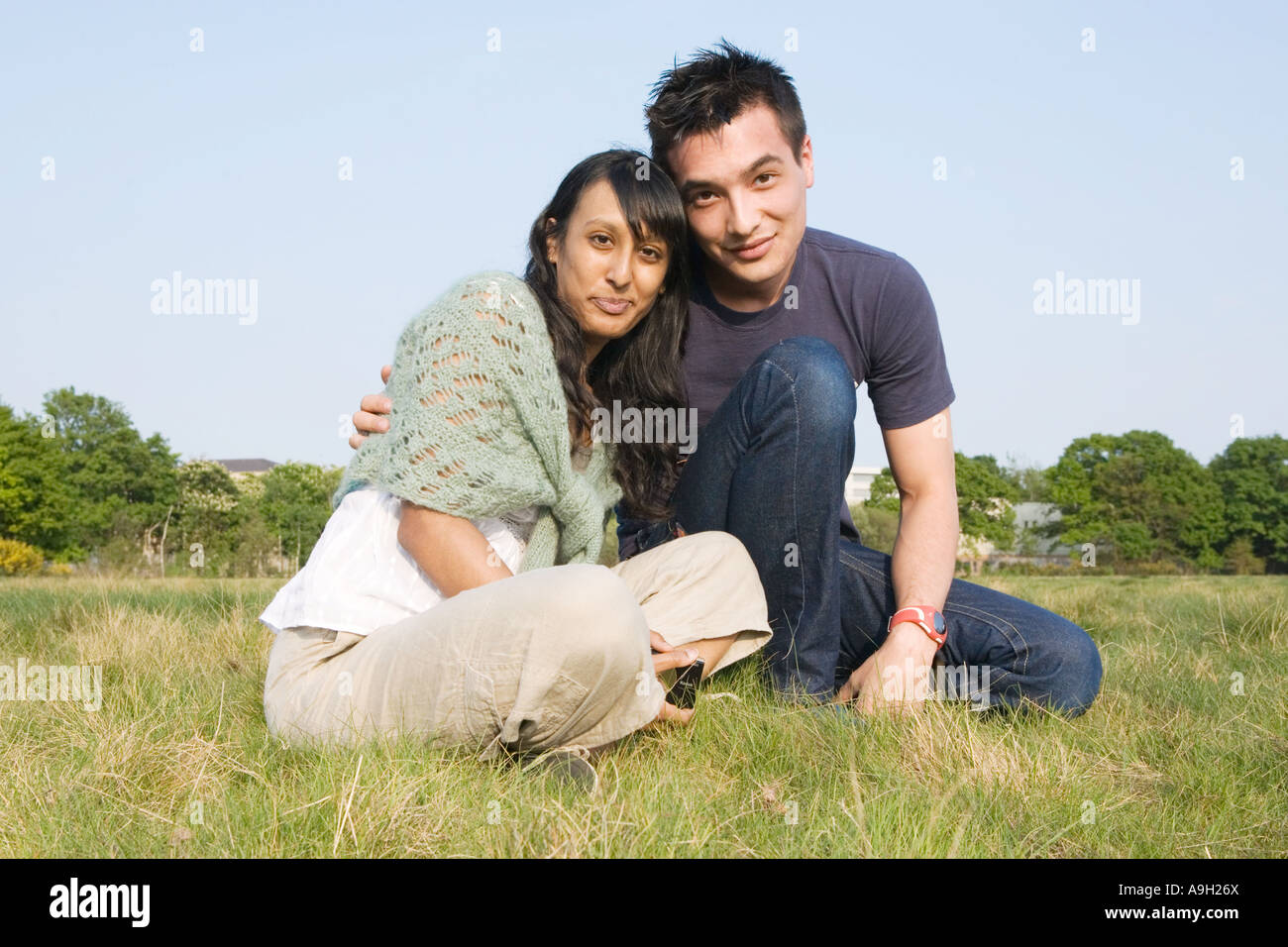 Couple sitting in a park Stock Photo - Alamy