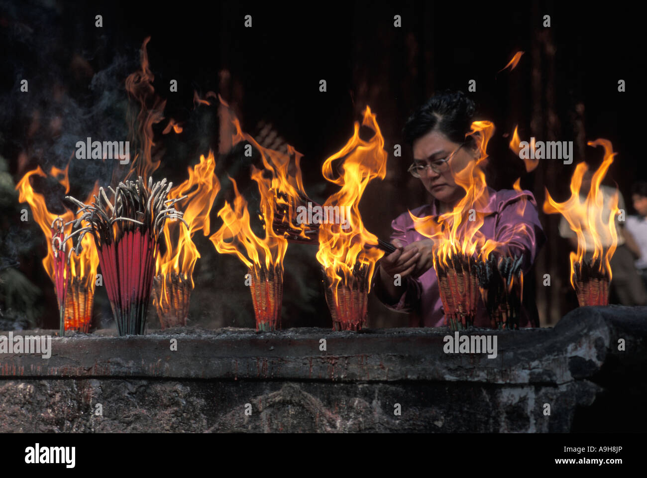 Woman making offerings of incense at a Buddhist shrine in Chengdu China ...