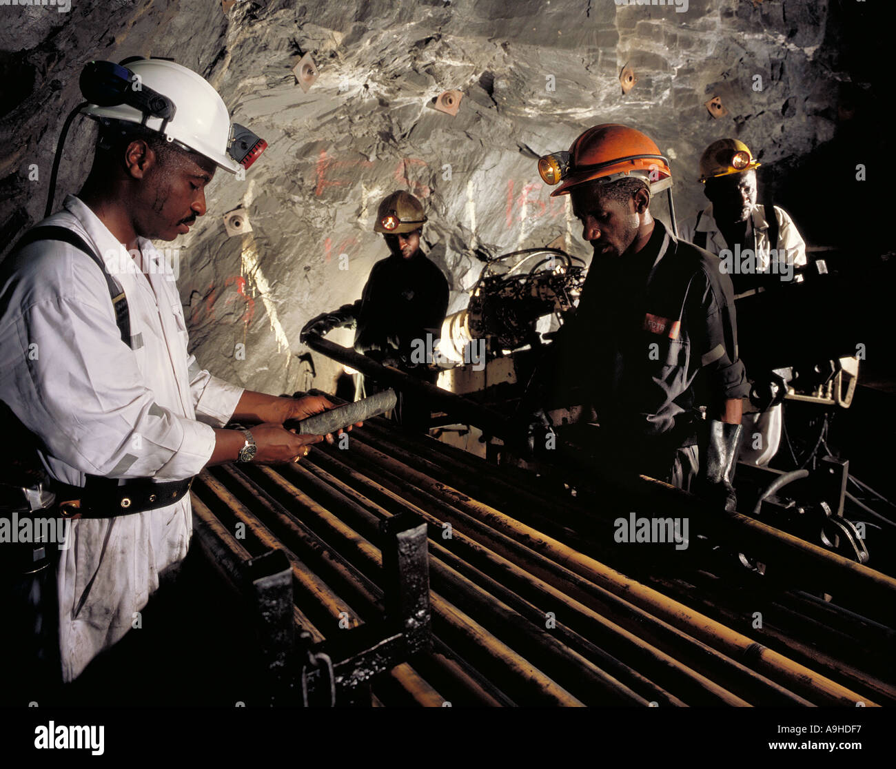 Geologist and miners inspecting core samples plus driller at underground gold mine in Obuasi, Ghana, West Africa Stock Photo