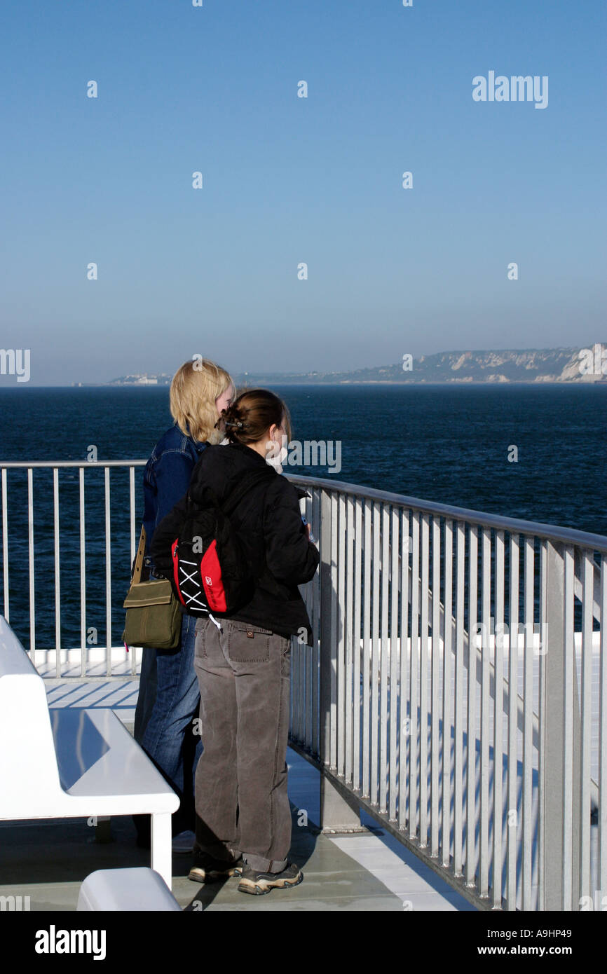 White Cliffs of Dover from stern of Speedferries catamaran with teenage girls looking back towards England early morning Stock Photo