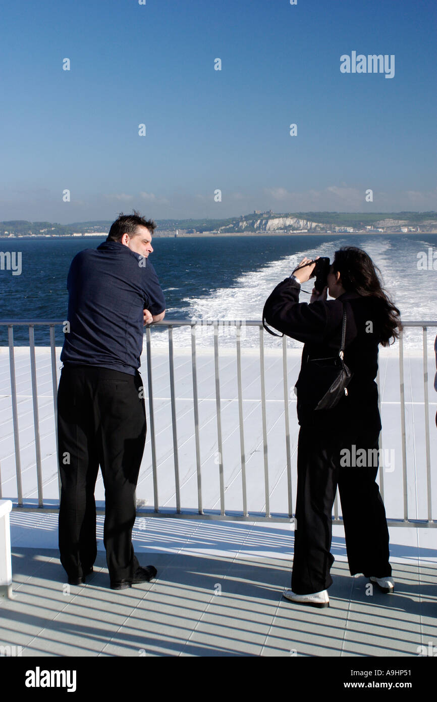 White Cliffs of Dover from stern of Speedferries catamaran with couple taking photograph early morning Stock Photo