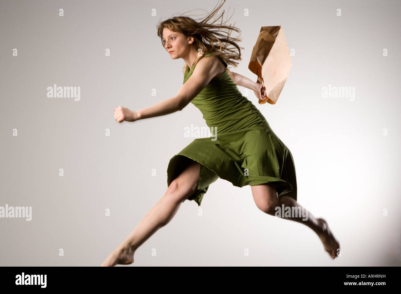 Young woman leaping in the air with a paperbag doing shopping Stock Photo