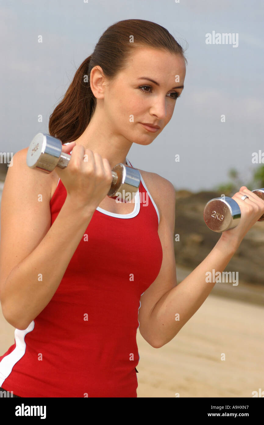 woman practicing training with dumbbells, wearing red t-shirt Stock Photo