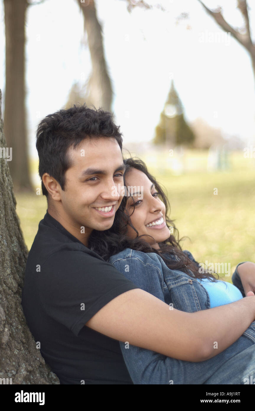 Portrait of couple leaning against tree Stock Photo - Alamy