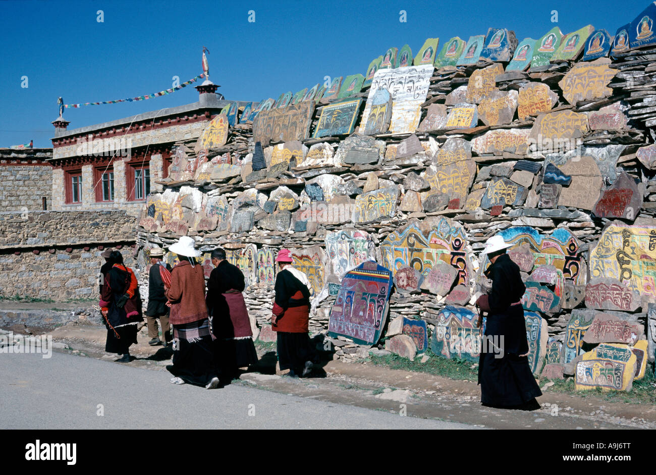 Locals doing their early morning prayer rounds passing a huge pile of Mani  stones at Chöde Gompa monastery. Stock Photo