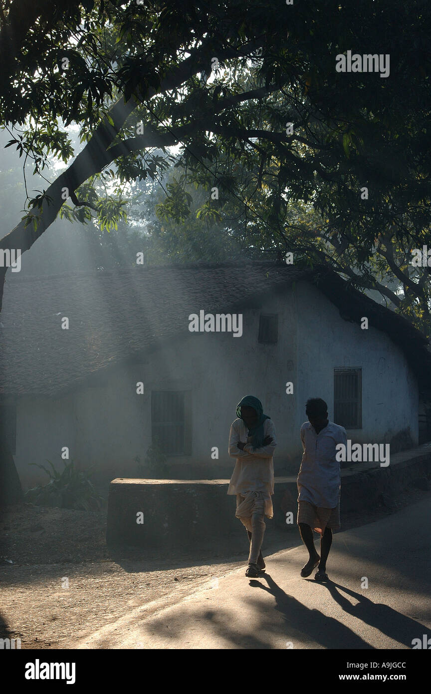 ANG99166 Two men walking Morning Sun Rays Sawantwadi Sindhudurga Maharashtra India Stock Photo