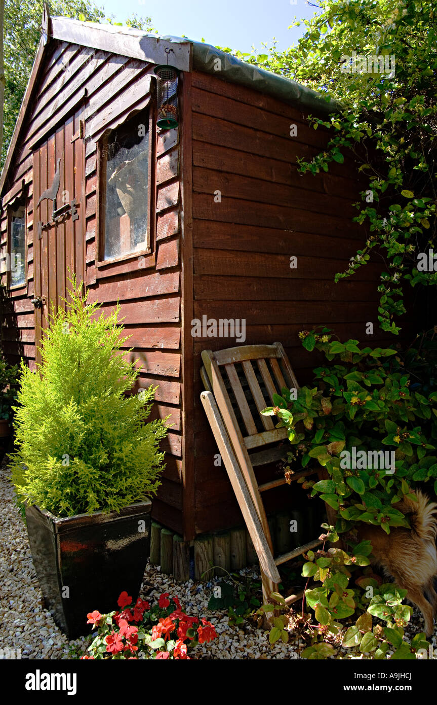 A folded chair leans carelessly against a wooden garden shed Stock