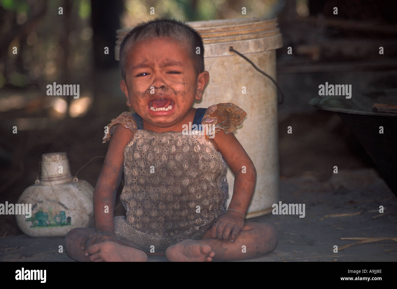 Baby crying outside house, rural Cambodia - Asia Stock Photo