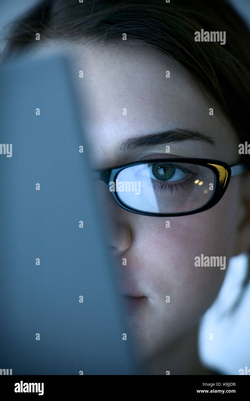 woman with glasses sitting in front of computer screen Stock Photo