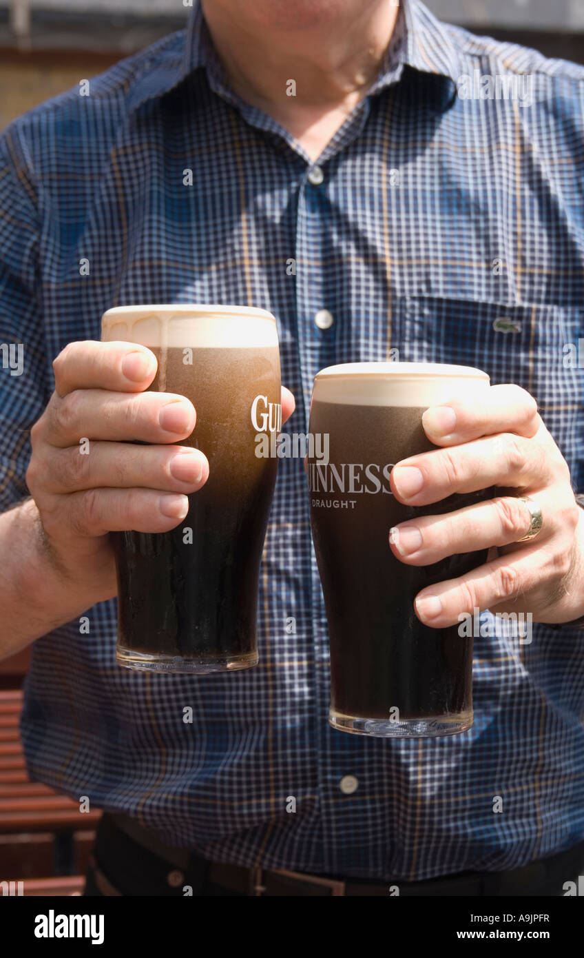 Man holding two foaming pints of Guinness beer Stock Photo