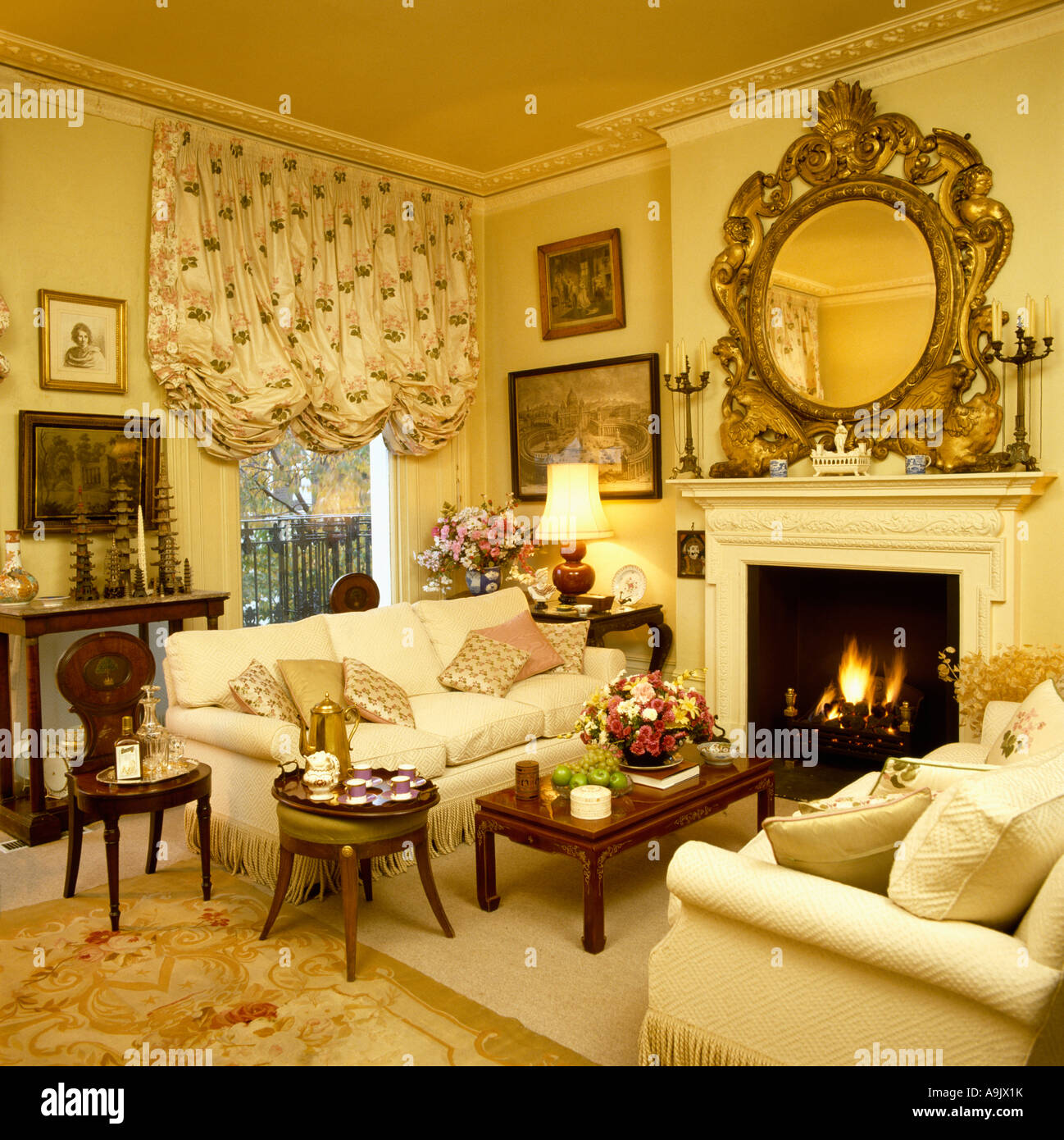 Large ornate gilt mirror above fireplace with lighted fire in yellow
