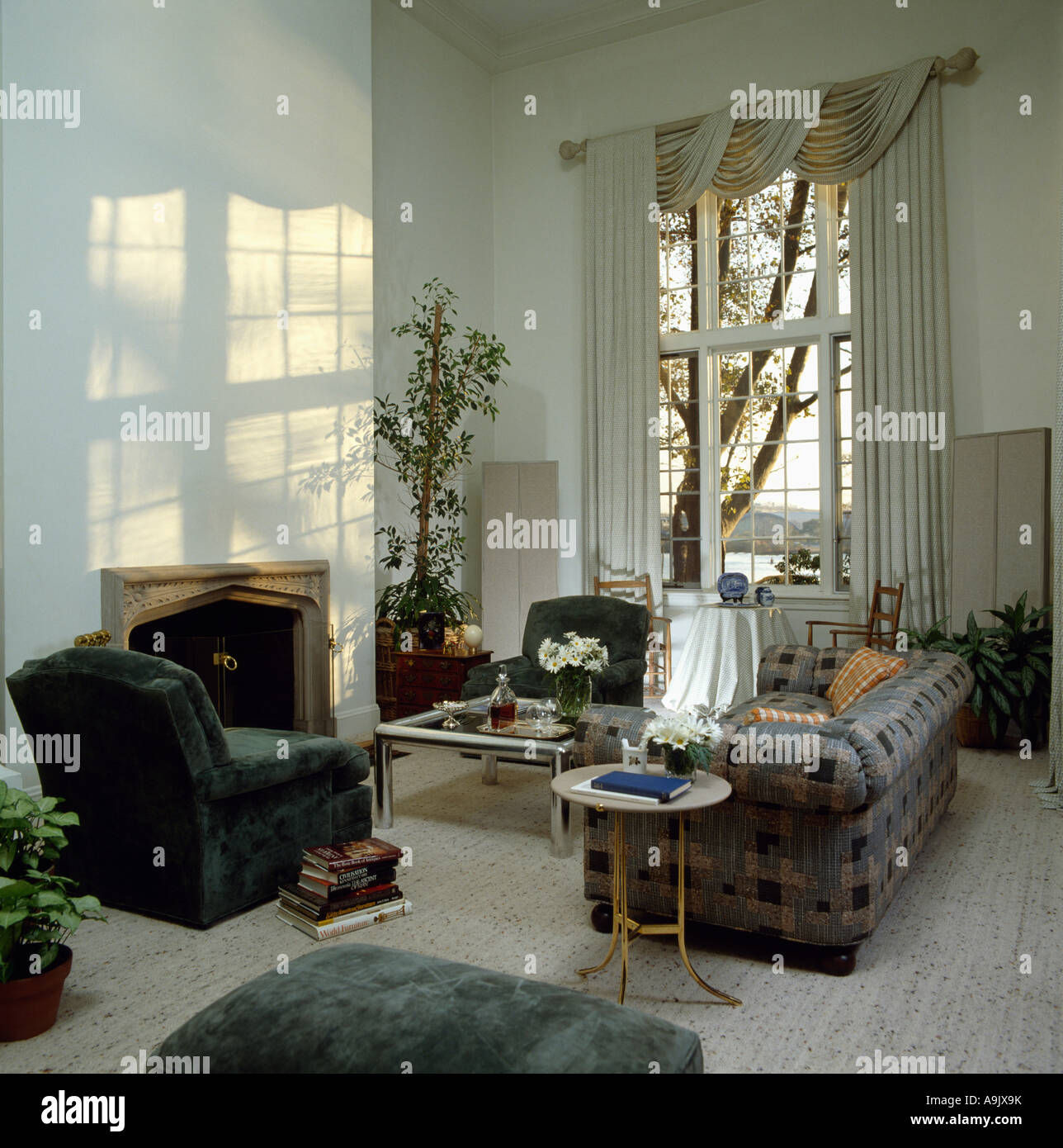 Chesterfield sofa and green velour armchair in eighties livingroom with tall window Stock Photo