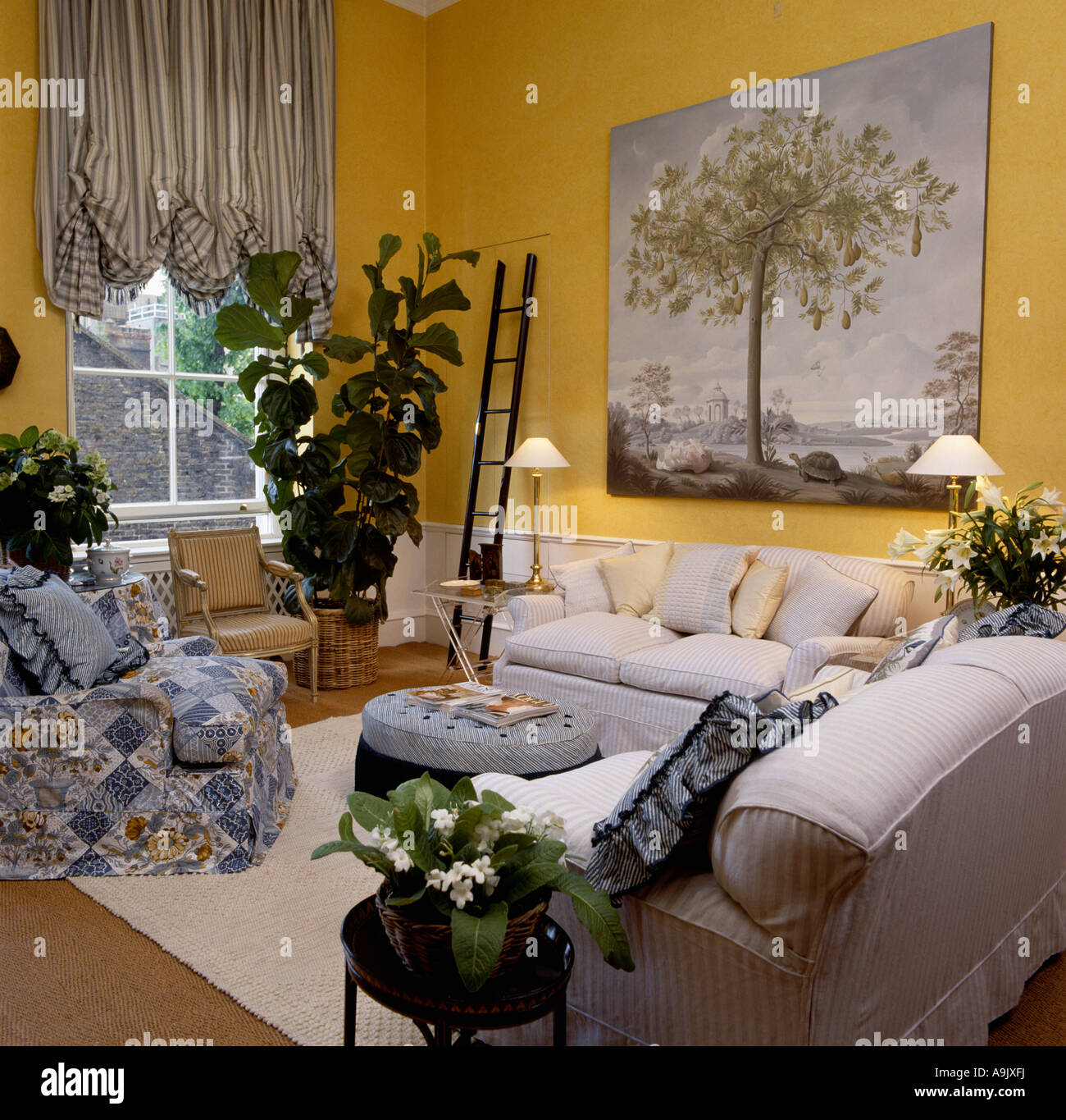White sofas in yellow sitting room with large picture and striped