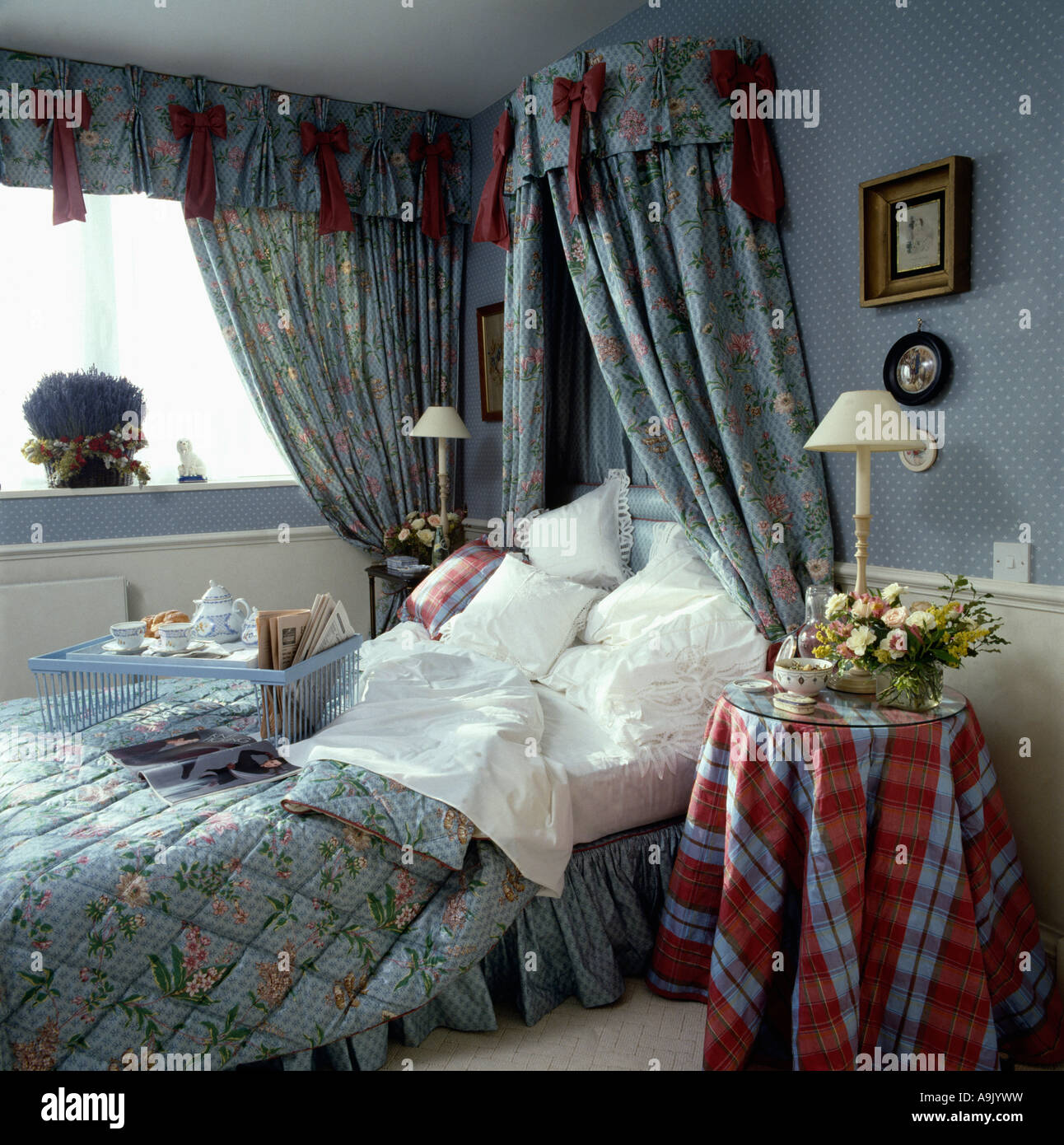 Patterned blue quilt and matching drapes on bed with breakfast tray and white pillows in
