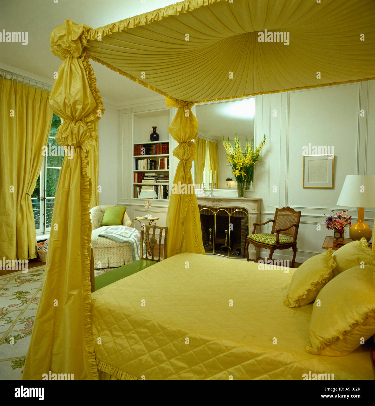 Fourposter bed with yellow silk wrapped canopy and posts and quilt in