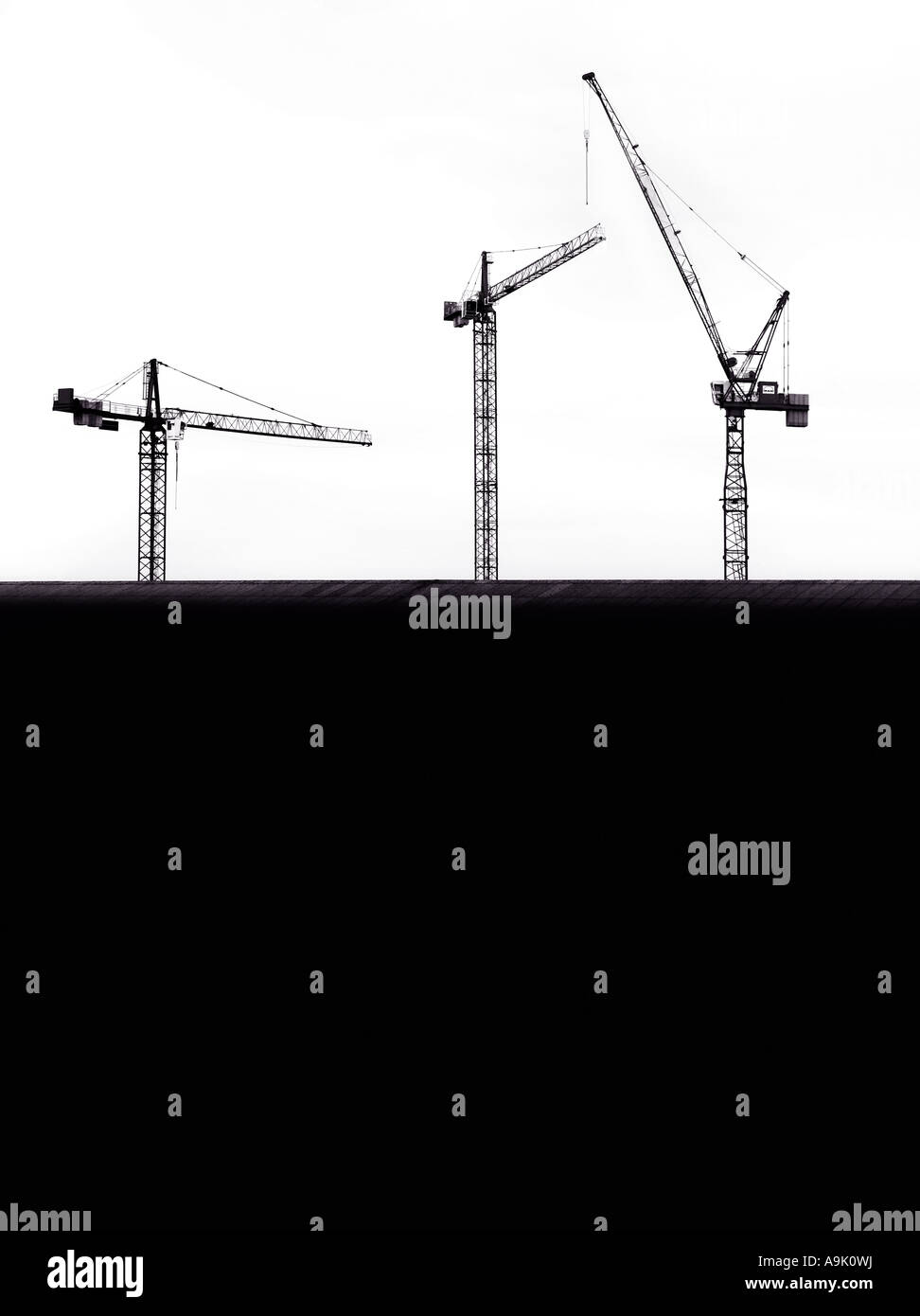 three cranes behind a building Stock Photo