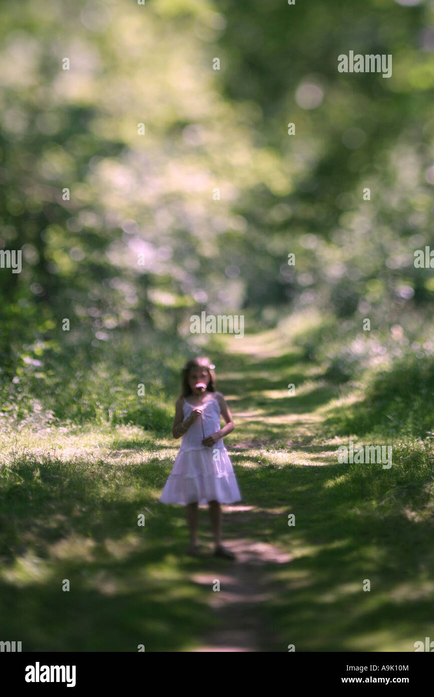 a young girl in a white dress holding a flower Stock Photo - Alamy