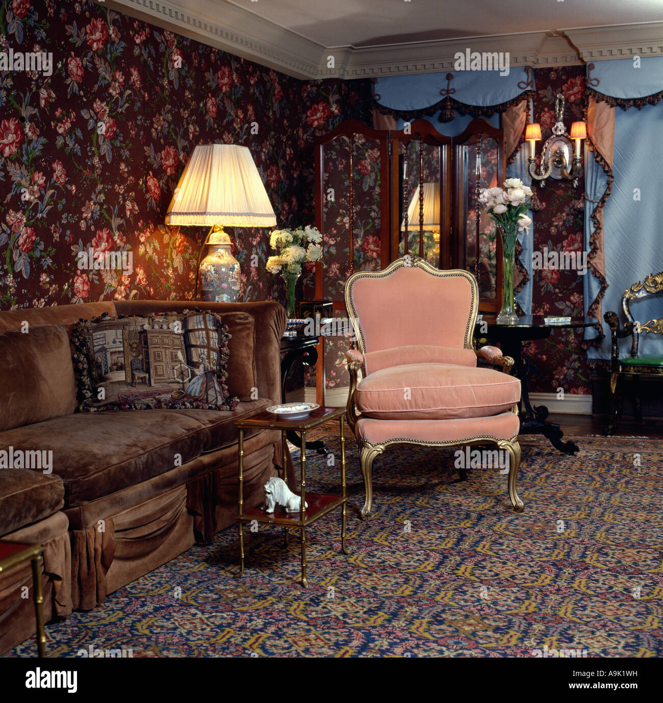 Brown velvet sofa and pink armchair in eighties livingroom with patterned wallpaper and carpet Stock Photo
