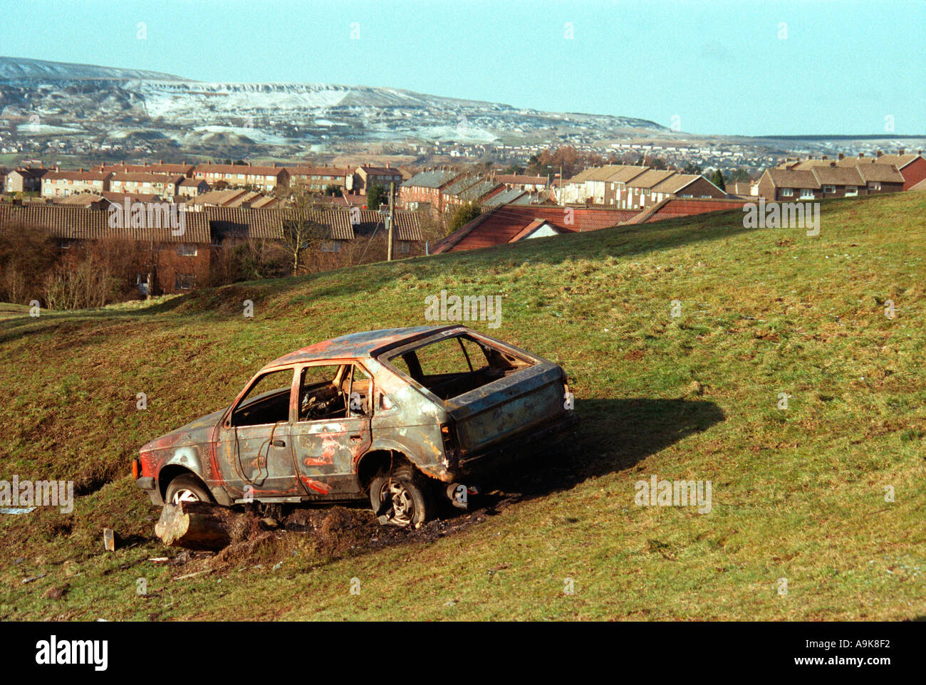 BURNT OUT ABANDONED STOLEN CAR ON THE GURNOS COUNCIL ESTATE IN MERTHYR TYDFIL IN SOUTH WALES, U.K. Stock Photo