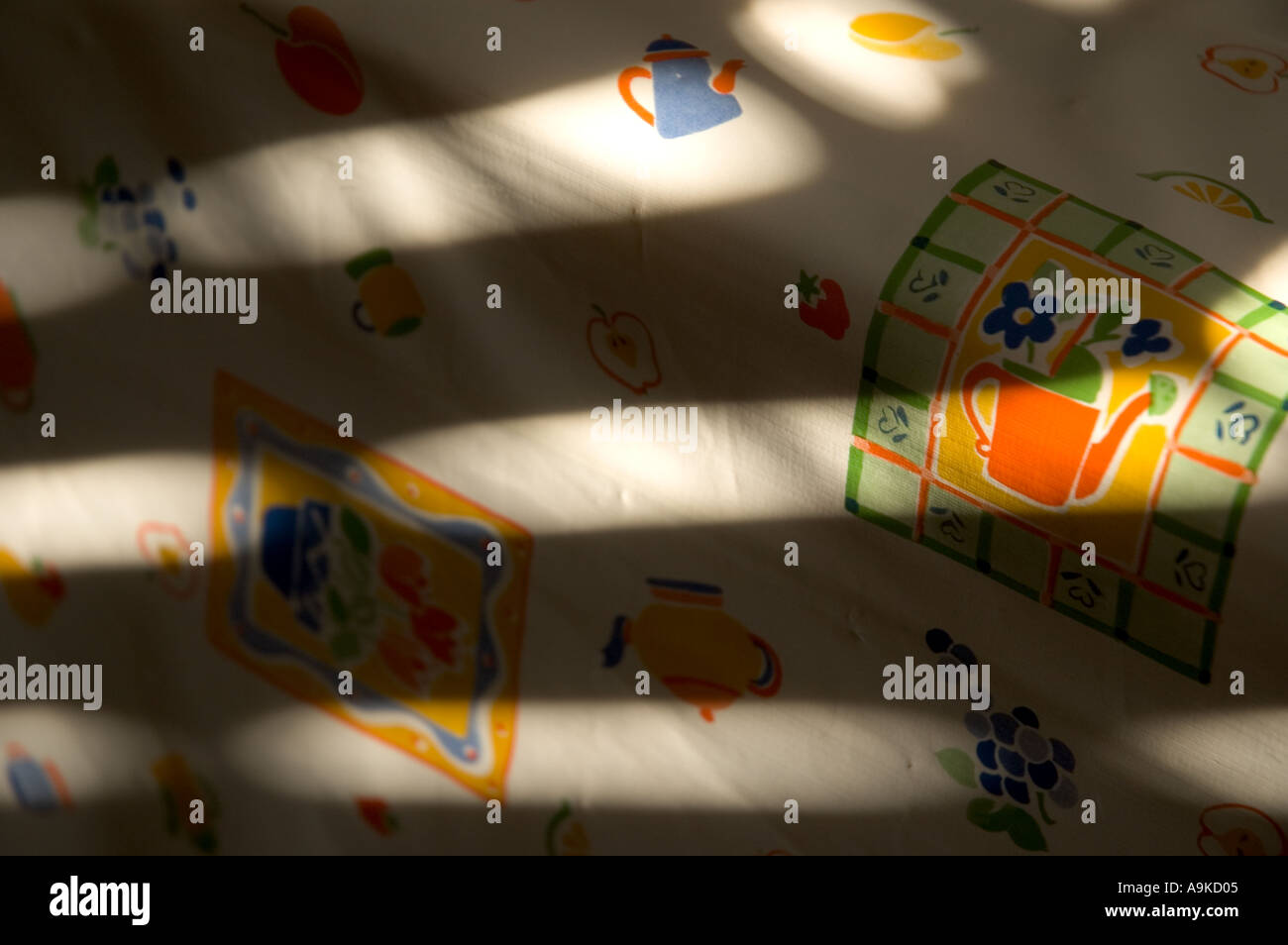 sun rays through shutters shining onto table cloth with naive drawings ...