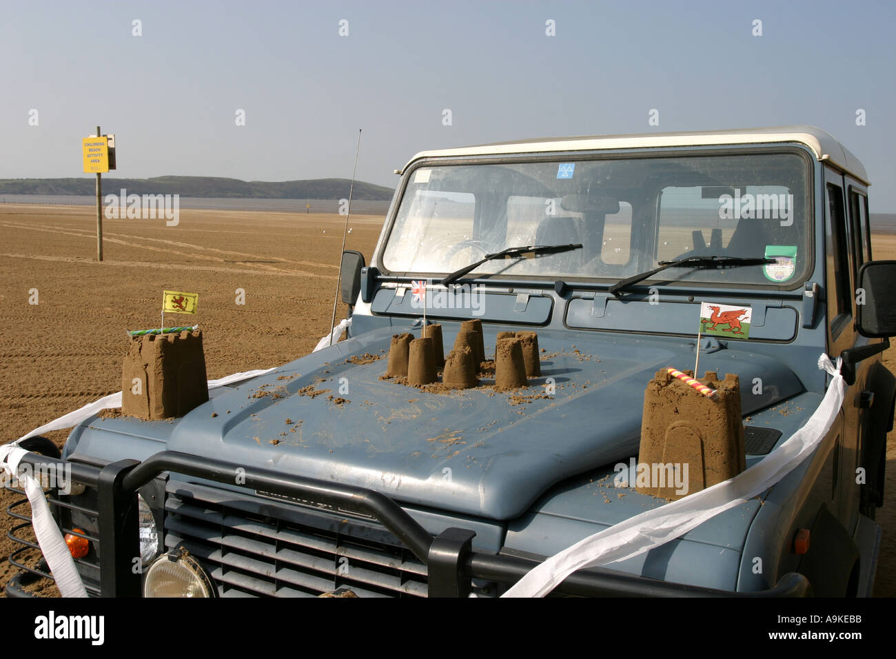 Sandcastles and paper flags built on a Land Rover on the beach at Weston super Mare Stock Photo