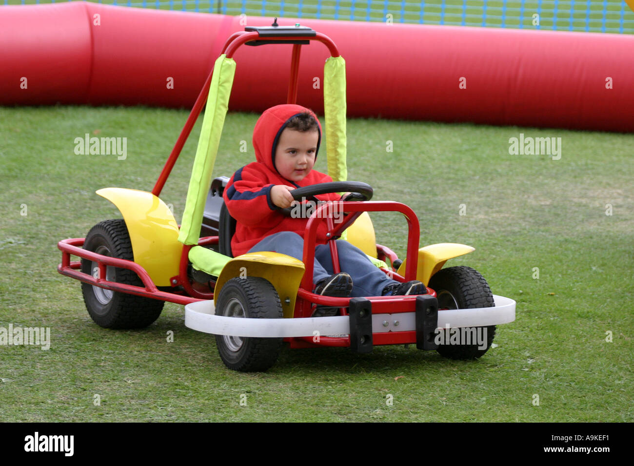 A Three Year Old Boy Drives An Electric Go Kart Around A Small