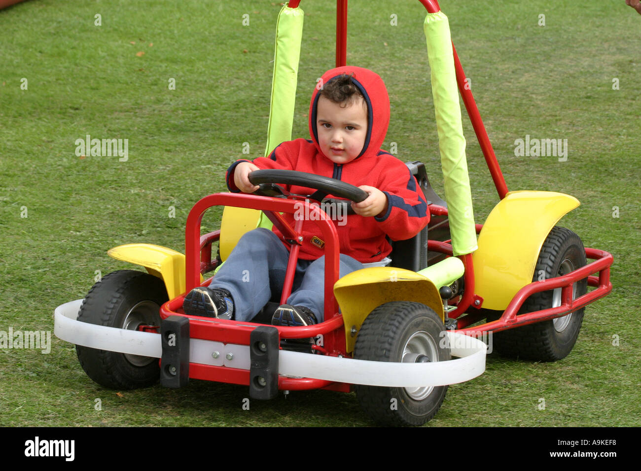 A Three Year Old Boy Drives An Electric Go Kart Around A Small