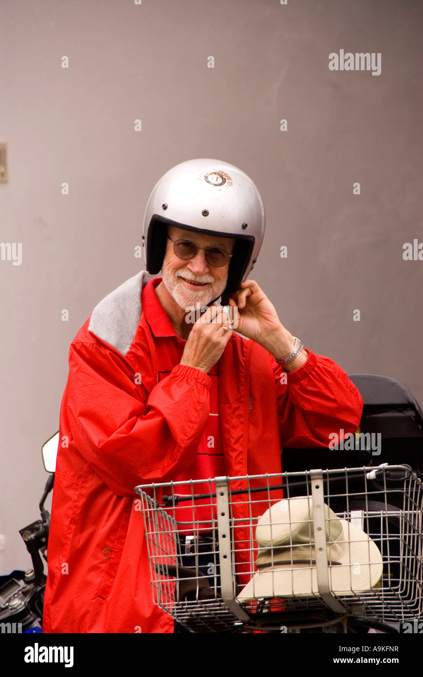 Bermuda elderly older old man in red rain coat helmet beside motor