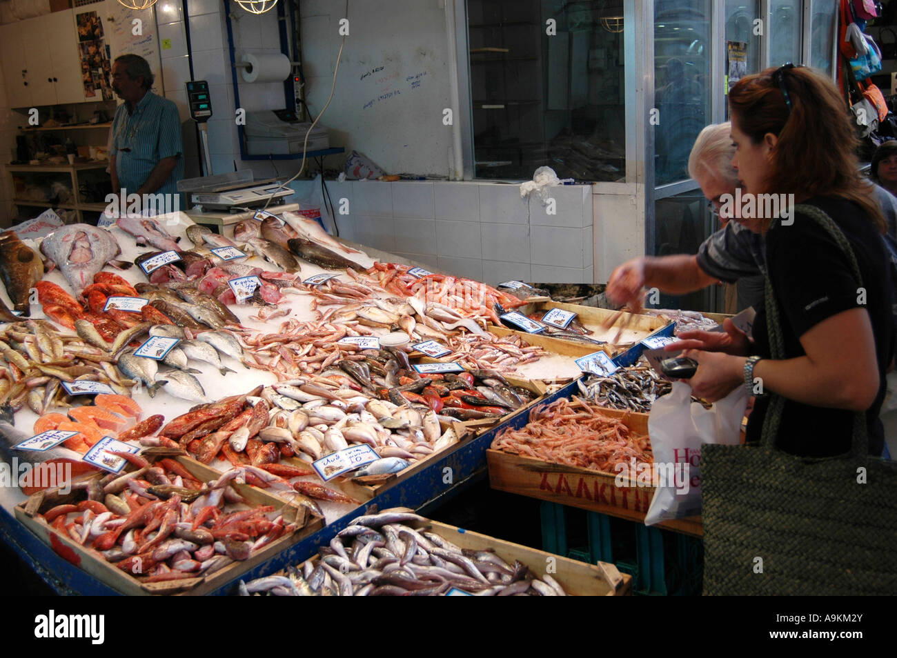 Customer buying from fresh wet fish stall in local street market Chania Crete Stock Photo
