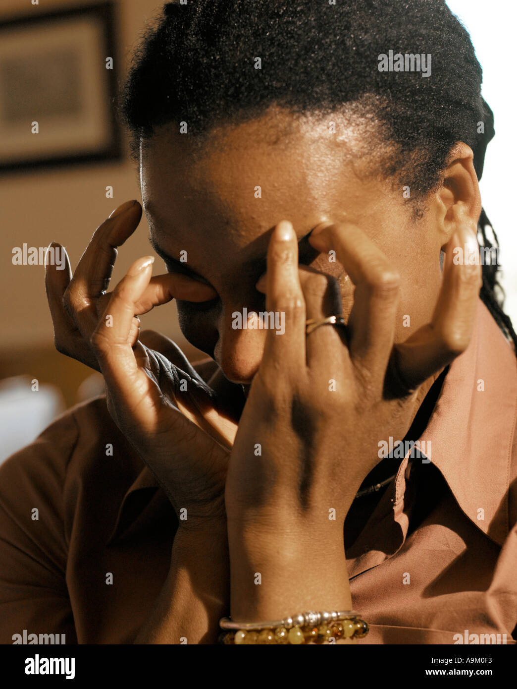 Afro-Caribbean woman rubbing eyes with hands Stock Photo