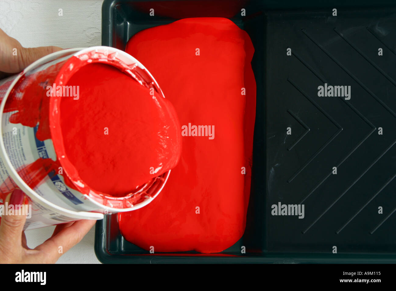 Pouring red paint into paint tray Stock Photo Alamy