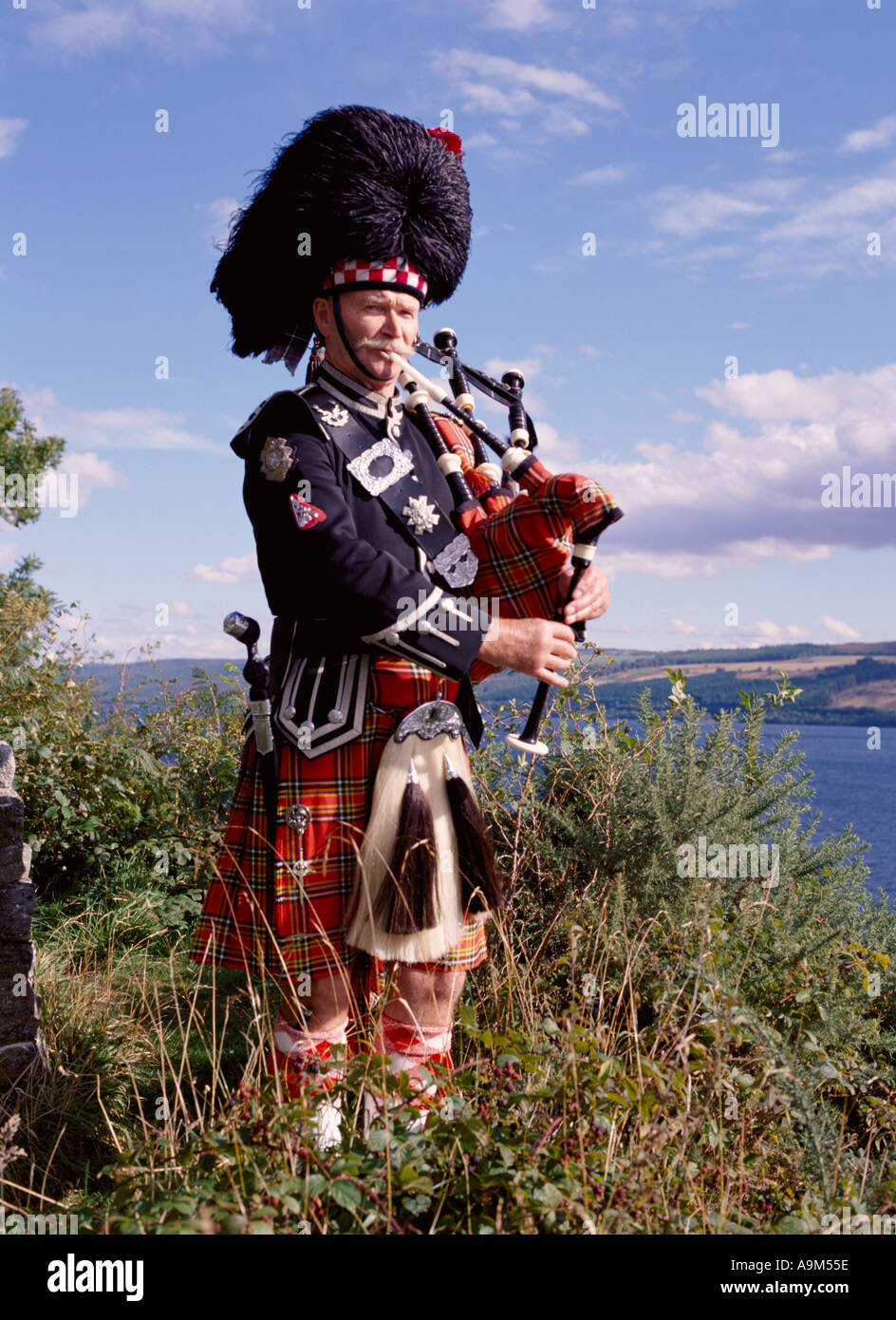 dh Scottish highlander BAGPIPES SCOTLAND Kilt Highland Clan dress highlands bagpiper lone piper playing traditional tartan music man Stock Photo