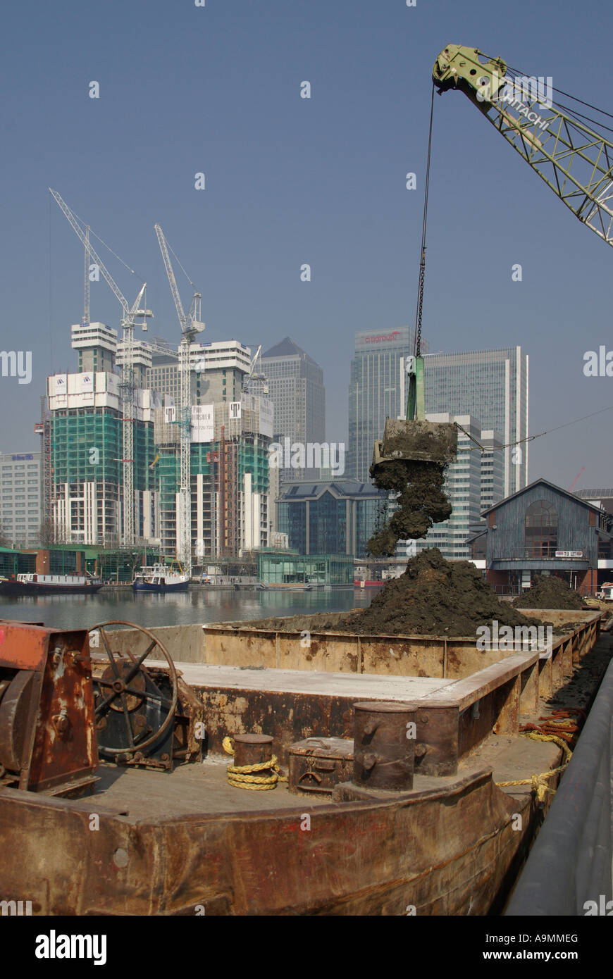 Construction building site crane loading barge with excavated earth from adjacent foundation work Inner Millwall Dock East London Docklands England UK Stock Photo