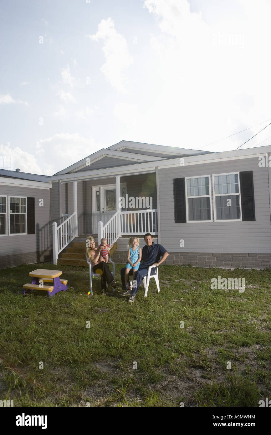 Portrait of a bluecollar family sitting in front of a trailer home