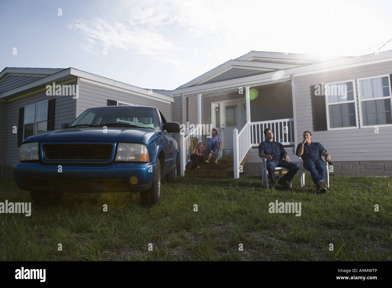 Two bluecollar families sitting on front lawn of trailer home Stock Photo Alamy