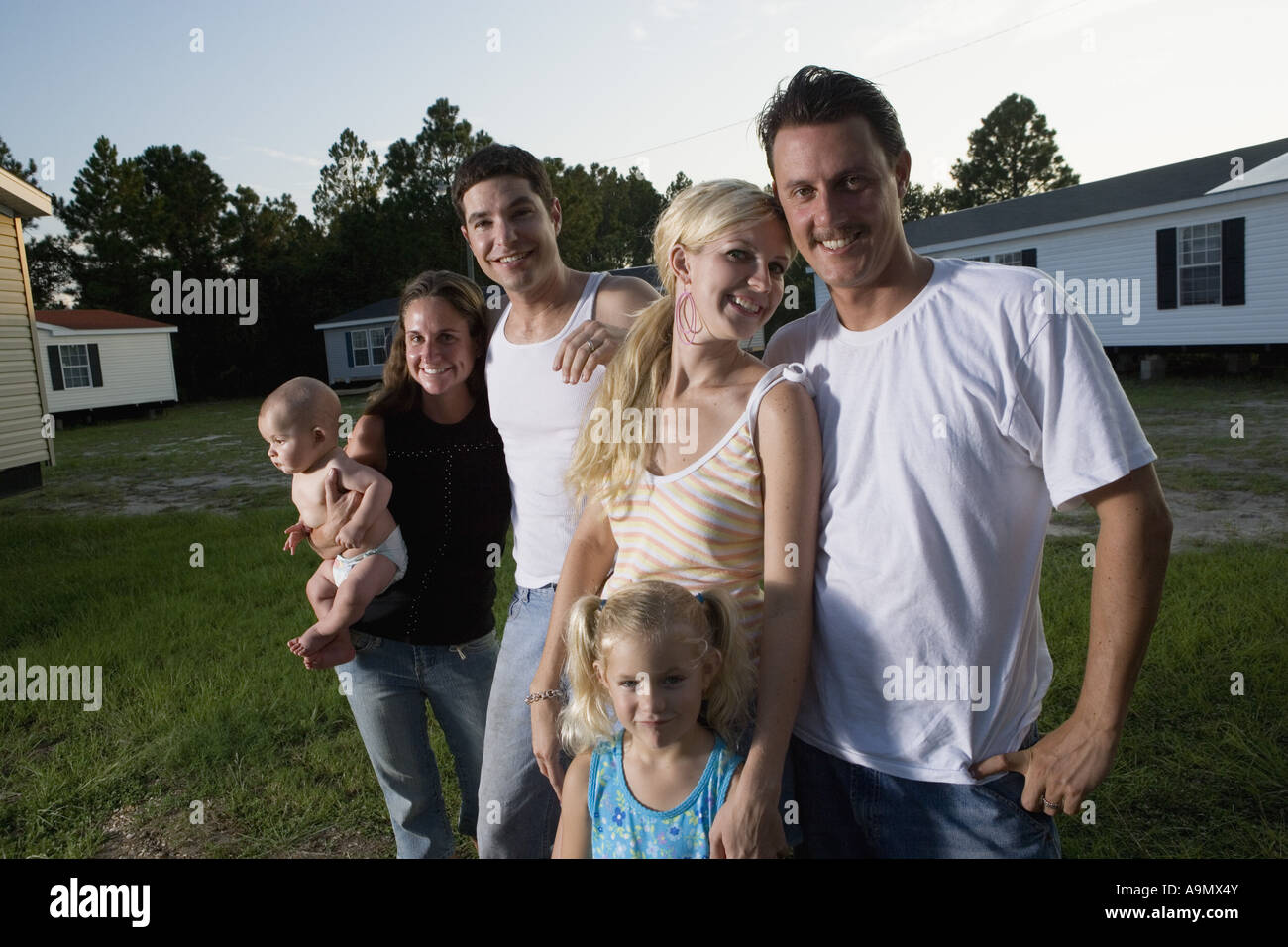 Portrait of two bluecollar families standing in front of trailer homes