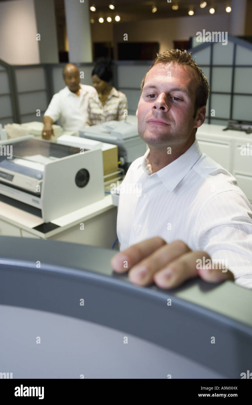 Office worker looking over cubicle wall near office equipment Stock