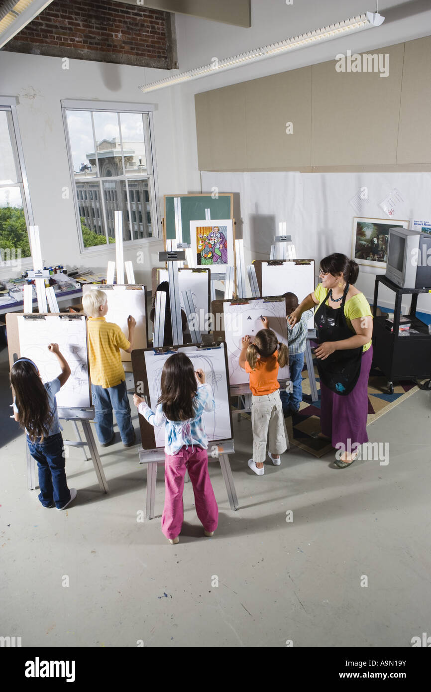 An art teacher with her students drawing on easels in art class Stock ...