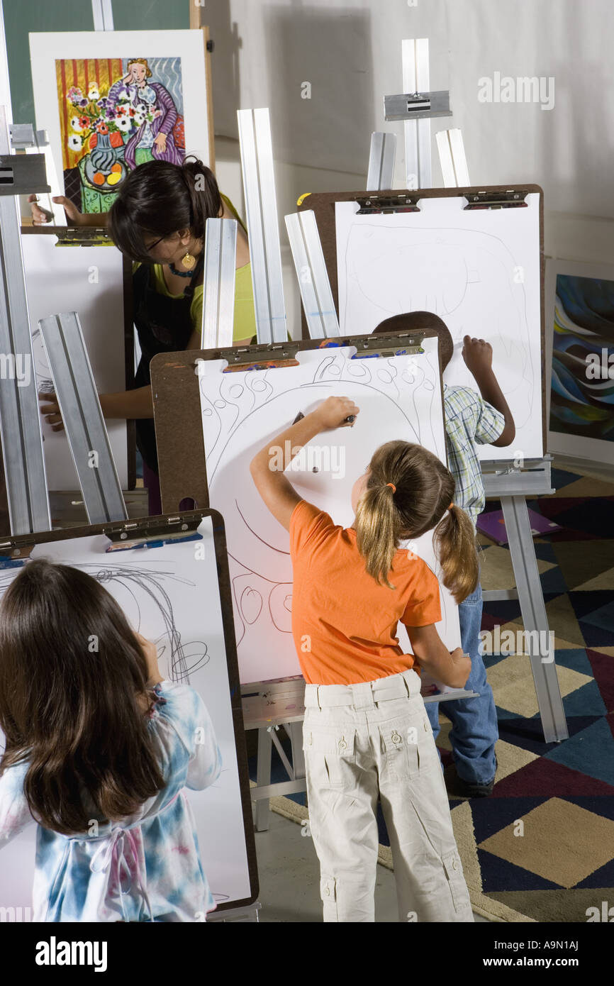 An art teacher with her students drawing on easels in art class Stock ...