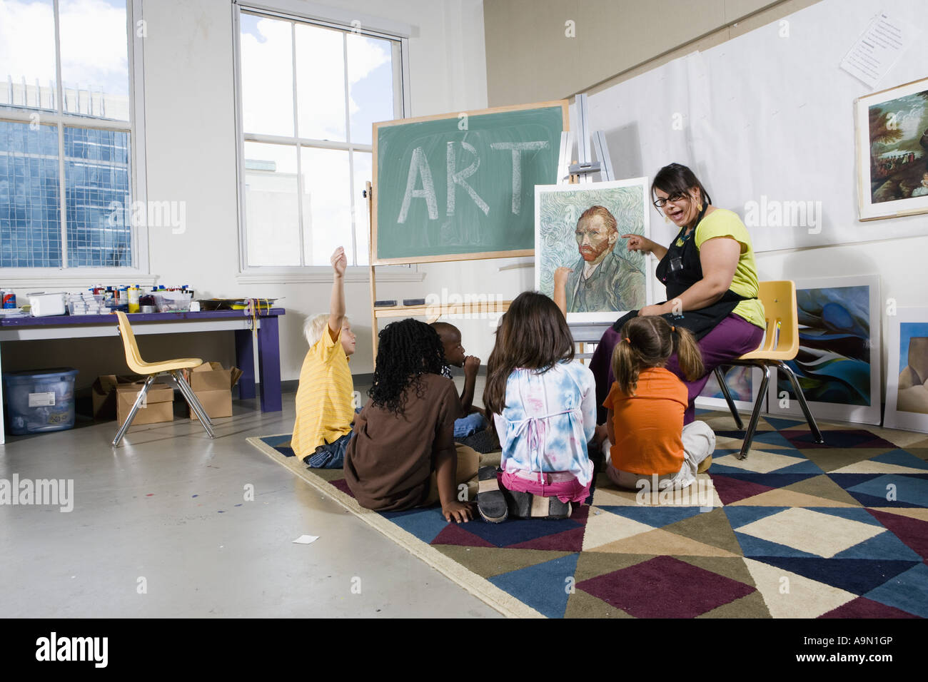 An art teacher by easel teaching her young students in art class Stock