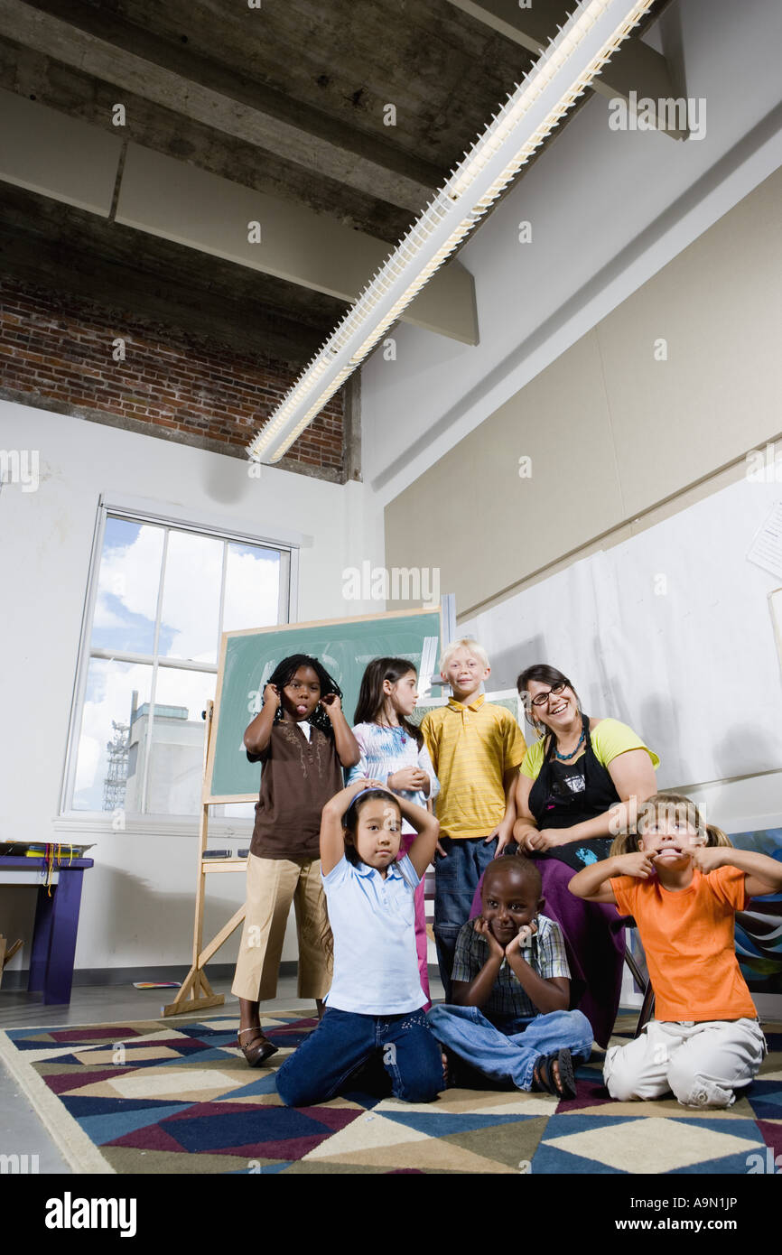 Portrait of an art teacher posing with her students making funny faces Stock Photo